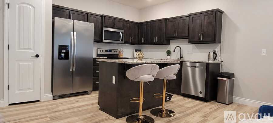 A kitchen with a black counter top and silver appliances.
