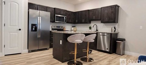 A kitchen with a black counter top and silver appliances.
