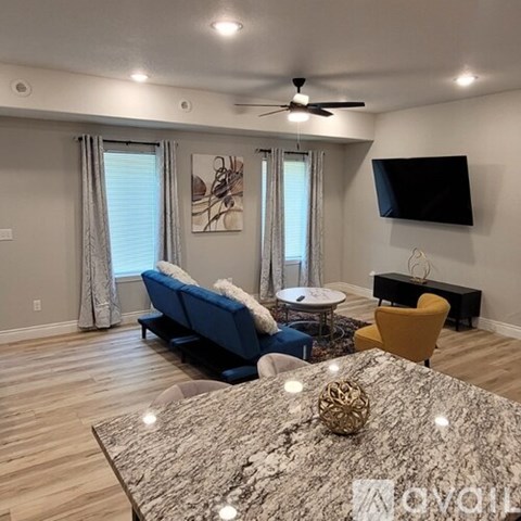A living room with a blue couch, a yellow chair, and a television mounted on the wall.