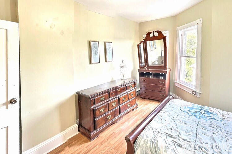A bedroom with a bed, dresser, and mirror.