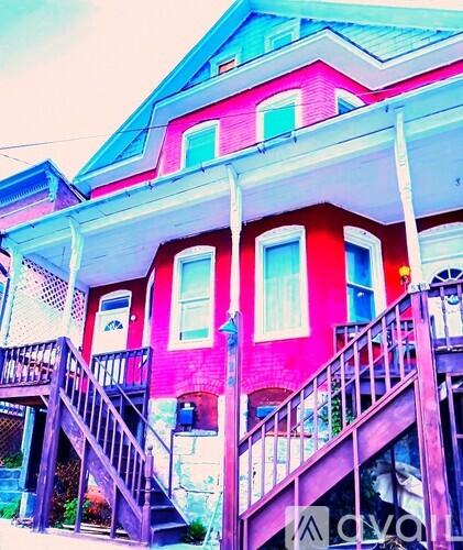 A pink and blue house with a wooden staircase leading to the front door.