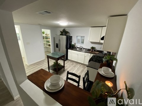 A kitchen with a table set for two and a plant on the counter.