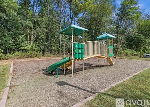 A playground with a green slide and two green canopies.