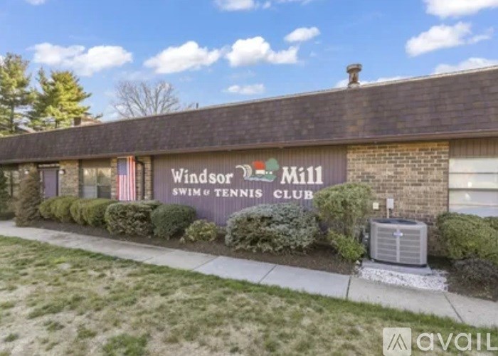 A building with the sign "Windsor Mill Swim & Tennis Club" on it.