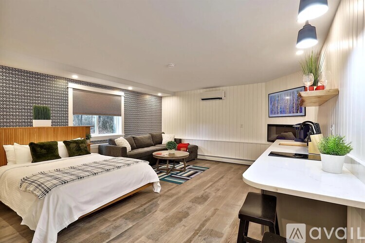 A bedroom with a bed, a couch, a table, and a window with blinds.
