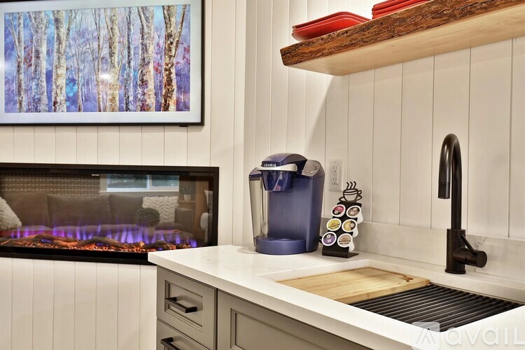 A kitchen with a wood stove and a painting of trees on the wall.