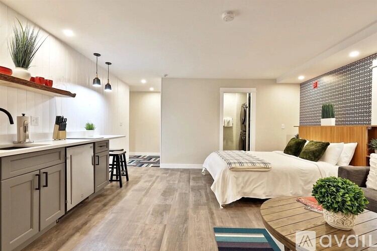 A well-lit, modern kitchen with a bar stool and a dining table with a plant on it.