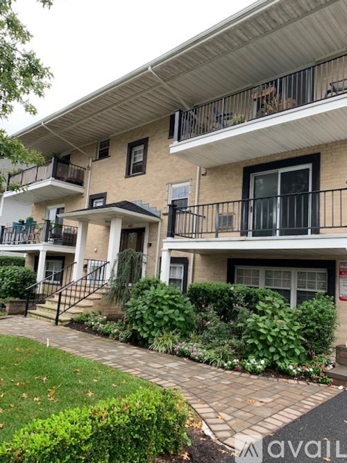 Apartment building with a balcony and a small garden in front.