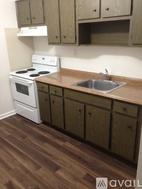A kitchen with a white stove and wooden cabinets.