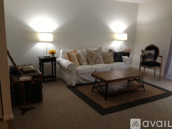 A living room with a white couch, a wooden coffee table, and two lamps.