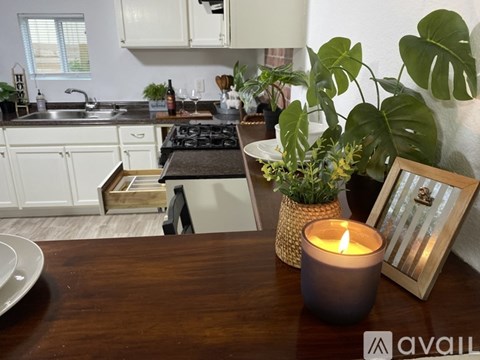 A modern kitchen with a wooden table holding a candle and a picture frame.