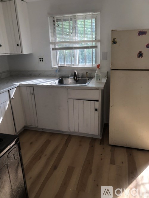 A kitchen with white cabinets and a wooden floor.