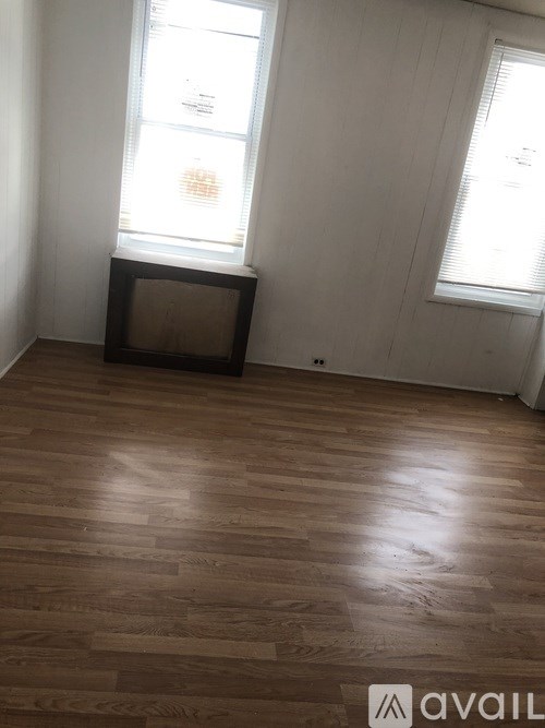 A room with wooden flooring and a window with blinds.