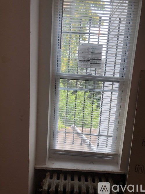 A window with blinds partially closed and a sign on the window.