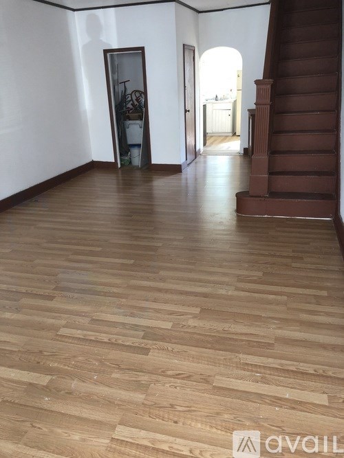 A hallway with wooden floors and a staircase.