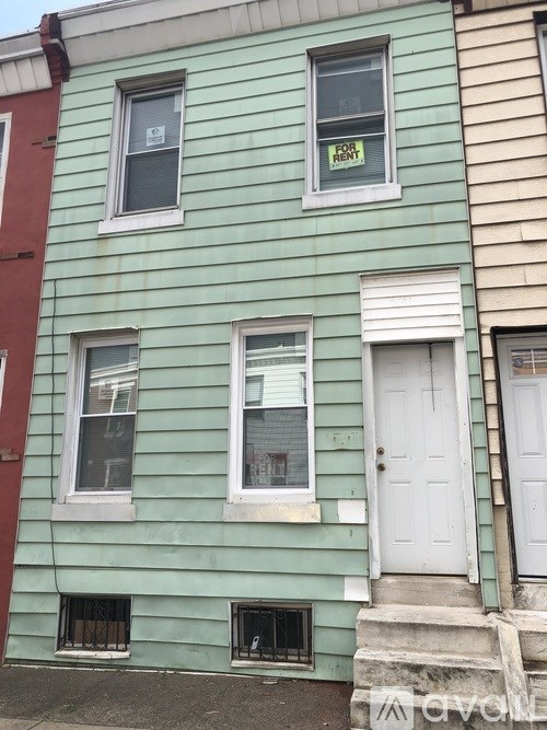 A green house with a for rent sign in the window.