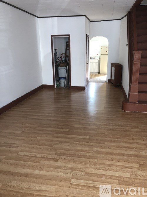 A room with wooden flooring and a staircase on the right.