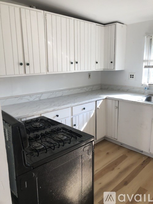A kitchen with a black stove top oven and white cabinets.