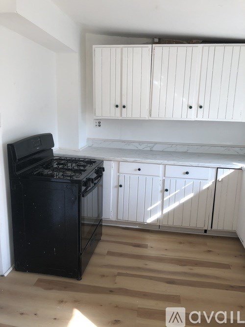 A black stove in a kitchen with wooden floors and white cabinets.
