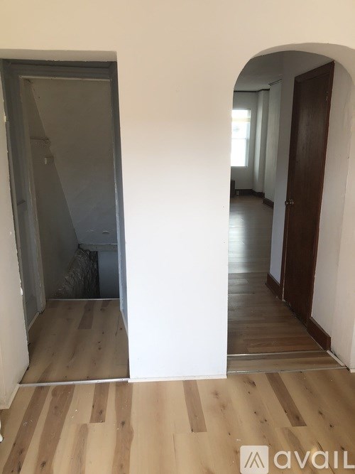 A hallway with a wooden floor and white walls.