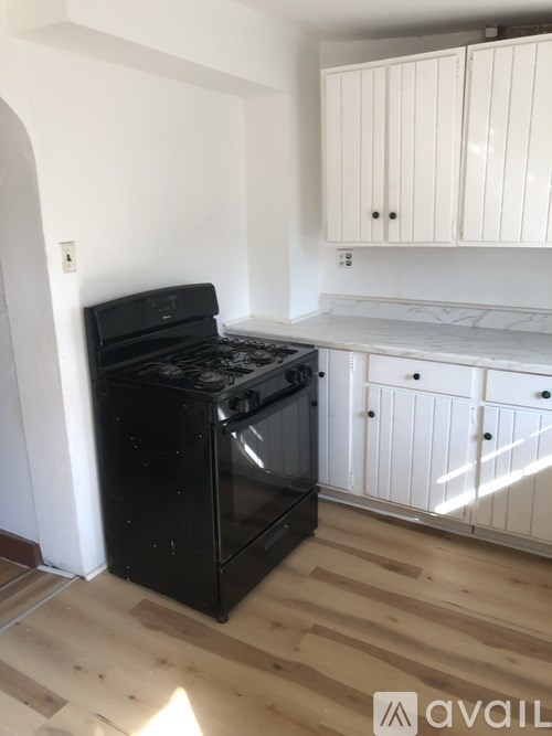 A black stove in a kitchen with wooden floors and white cabinets.
