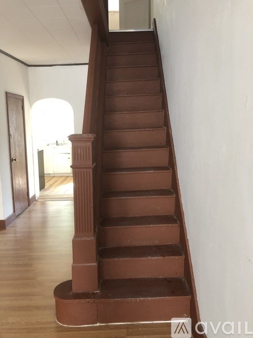 A brown staircase with a wooden handrail.