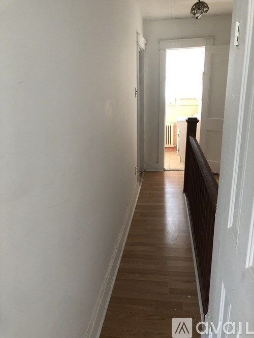 A long hallway with a white door at the end.