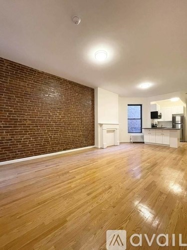 A room with wooden flooring and a brick wall.