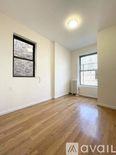 A room with wooden floors and a window with blinds.
