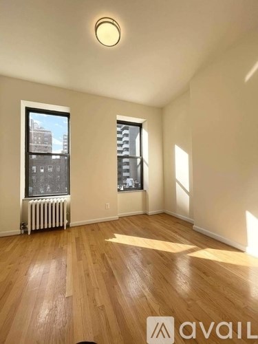 A room with wooden floors and two windows.