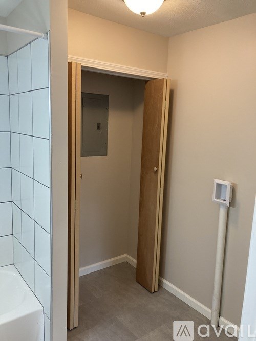 A white tiled shower area with a wooden door.