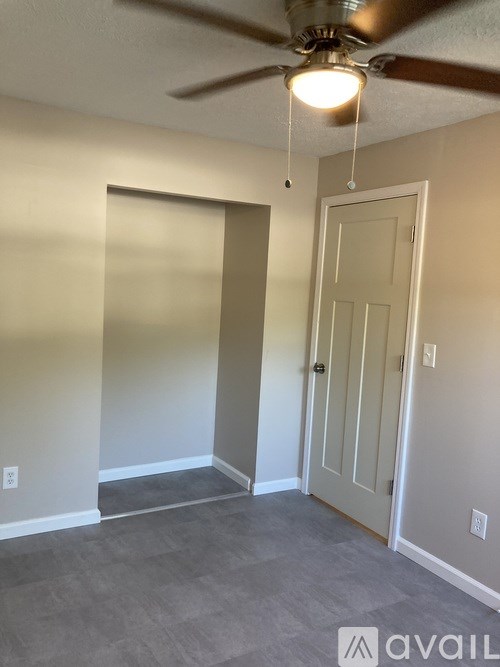 A room with a ceiling fan and a door.