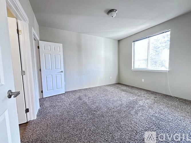 A room with a carpeted floor, a door, and a window.
