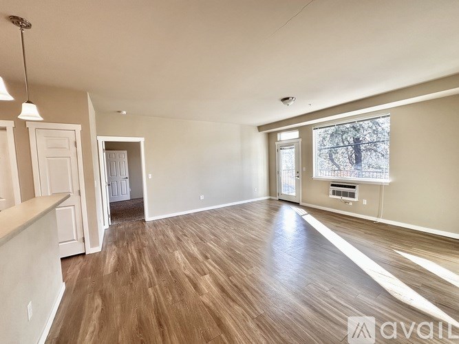A spacious room with wooden flooring and a large window.