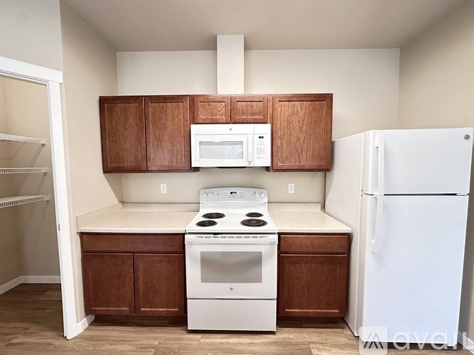 A kitchen with white appliances and wooden cabinets.