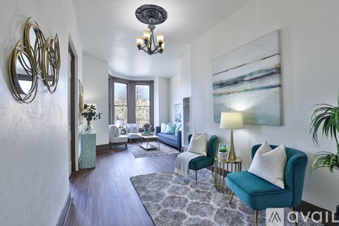 A living room with a blue chair and a painting on the wall.