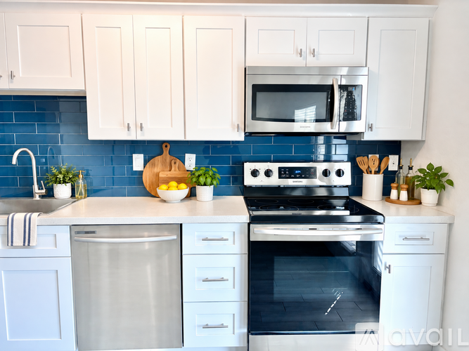 A kitchen with white cabinets and a blue backsplash.