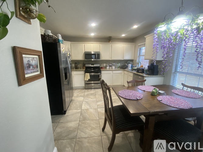 A kitchen with a table set for four with pink flowers.