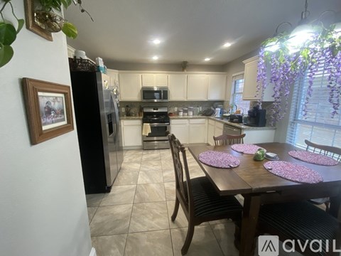 A kitchen with a table set for four with pink flowers.