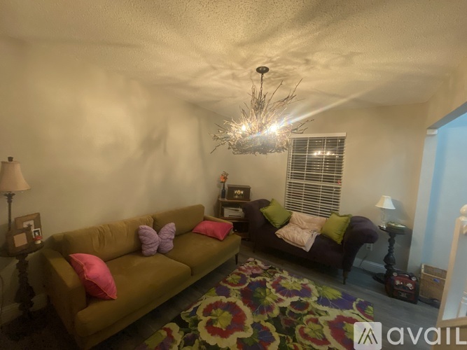 A living room with a brown couch and a chandelier.