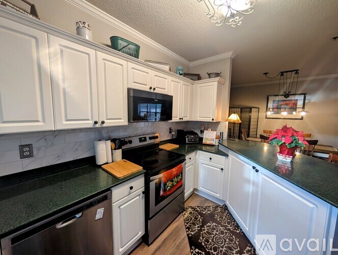 A kitchen with white cabinets and black countertops.