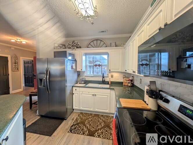 A kitchen with a stainless steel refrigerator and a black stove top oven.