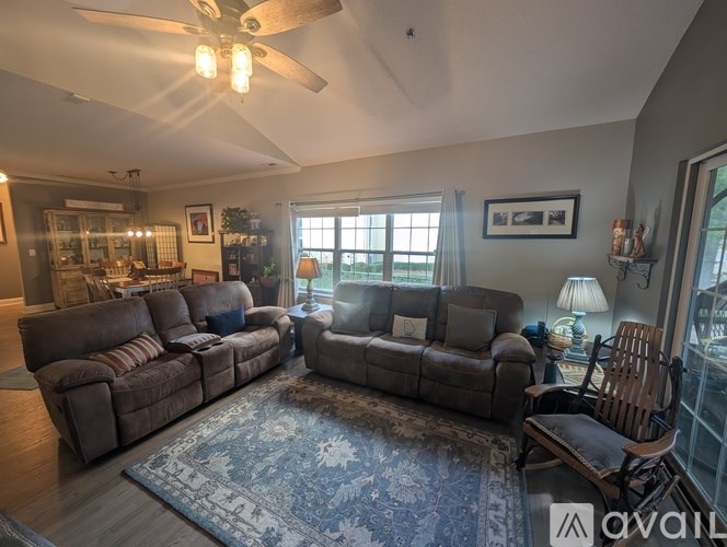 A living room with a rug, two couches, and a ceiling fan.