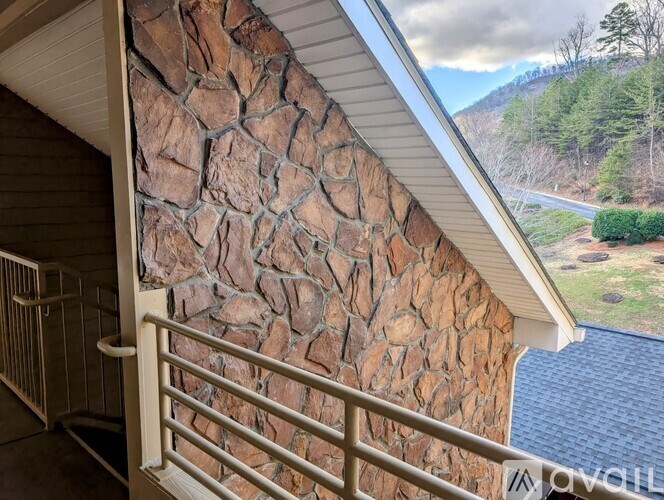 A stone wall on the side of a house with a metal railing.