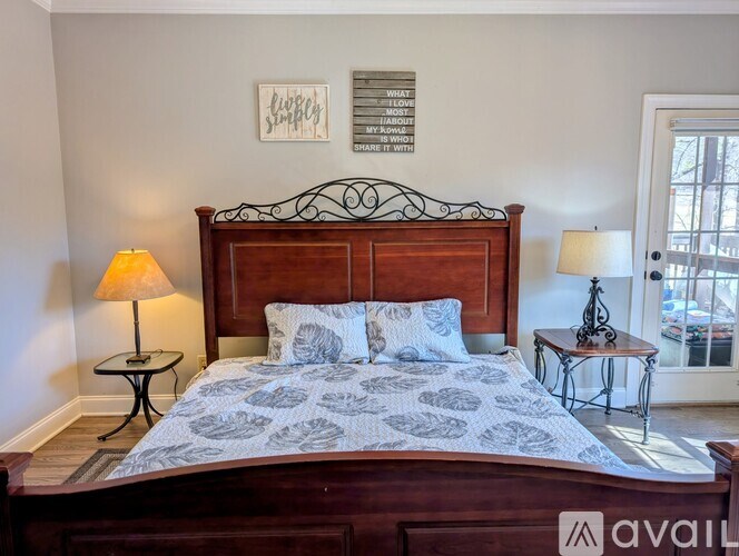 A bedroom with a bed, lamp, and a framed picture on the wall.
