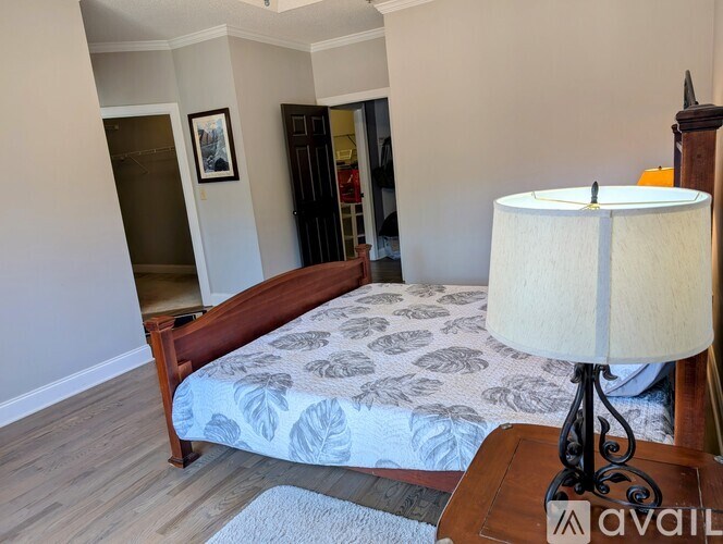 A bedroom with a bed, lamp, and a painting on the wall.