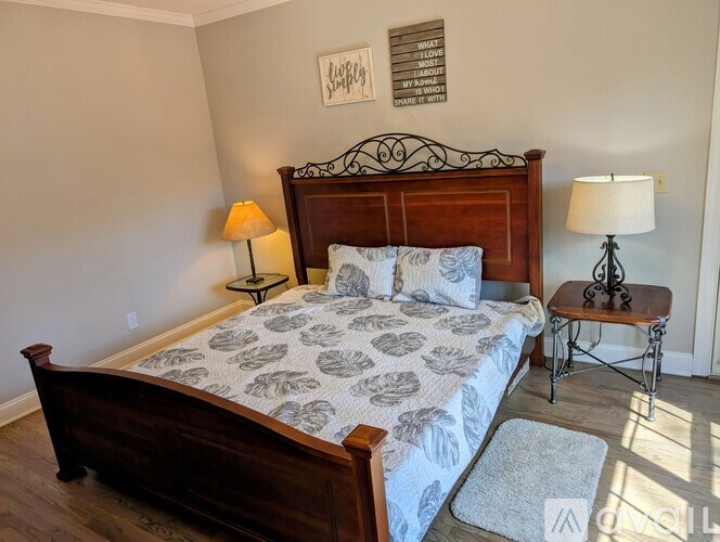 A bedroom with a large bed and a small table with a lamp on it.