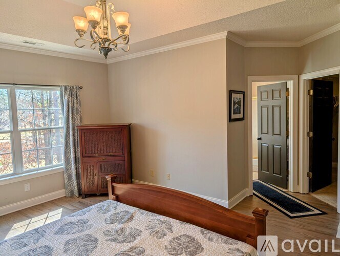 A bedroom with a large bed and a chandelier.