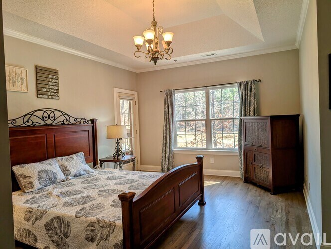 A bedroom with a large bed and a chandelier.