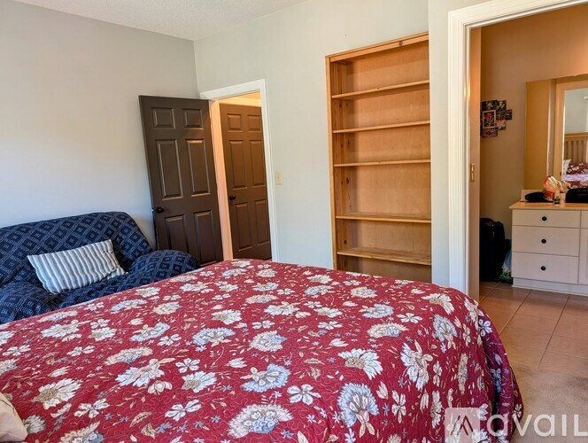 A bedroom with a floral bedspread and a wooden wardrobe.